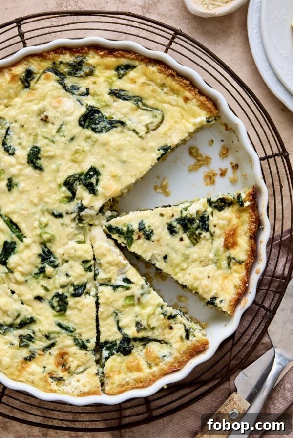Spinach Feta Quiche with Quinoa Crust in white round baking dish cut into pieces.