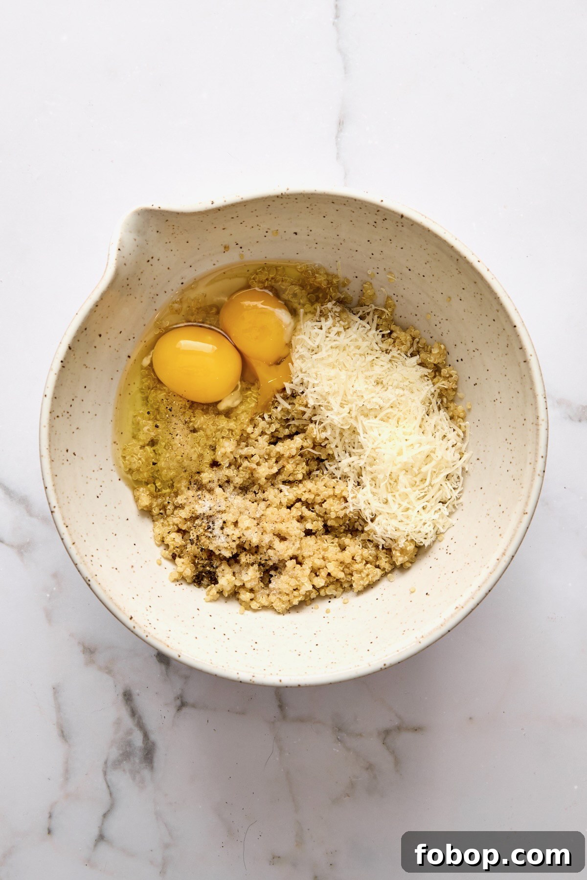 Cooked quinoa, eggs, and cheese in mixing bowl.
