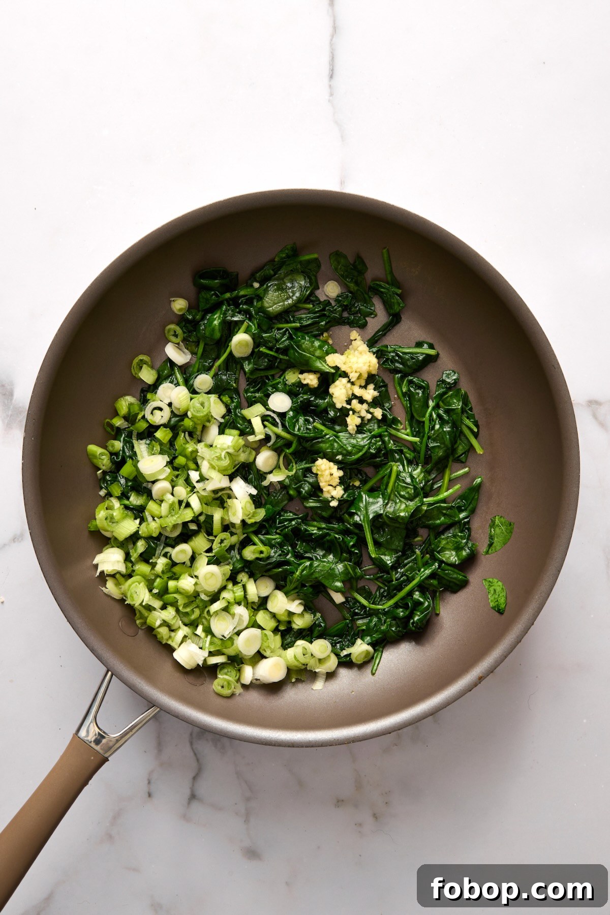 Cooked spinach and scallions in saute pan.