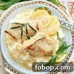 chicken tarragon plated with fresh tarragon, lemon slices and sauce on a bed of mashed potatoes