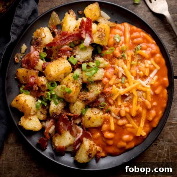 Creamy Scrambled Eggs with Sautéed Kale Breakfast Bowl 7 A black plate with baked beans topped with grated cheese on one side and a hearty potato and bacon hash on the other.