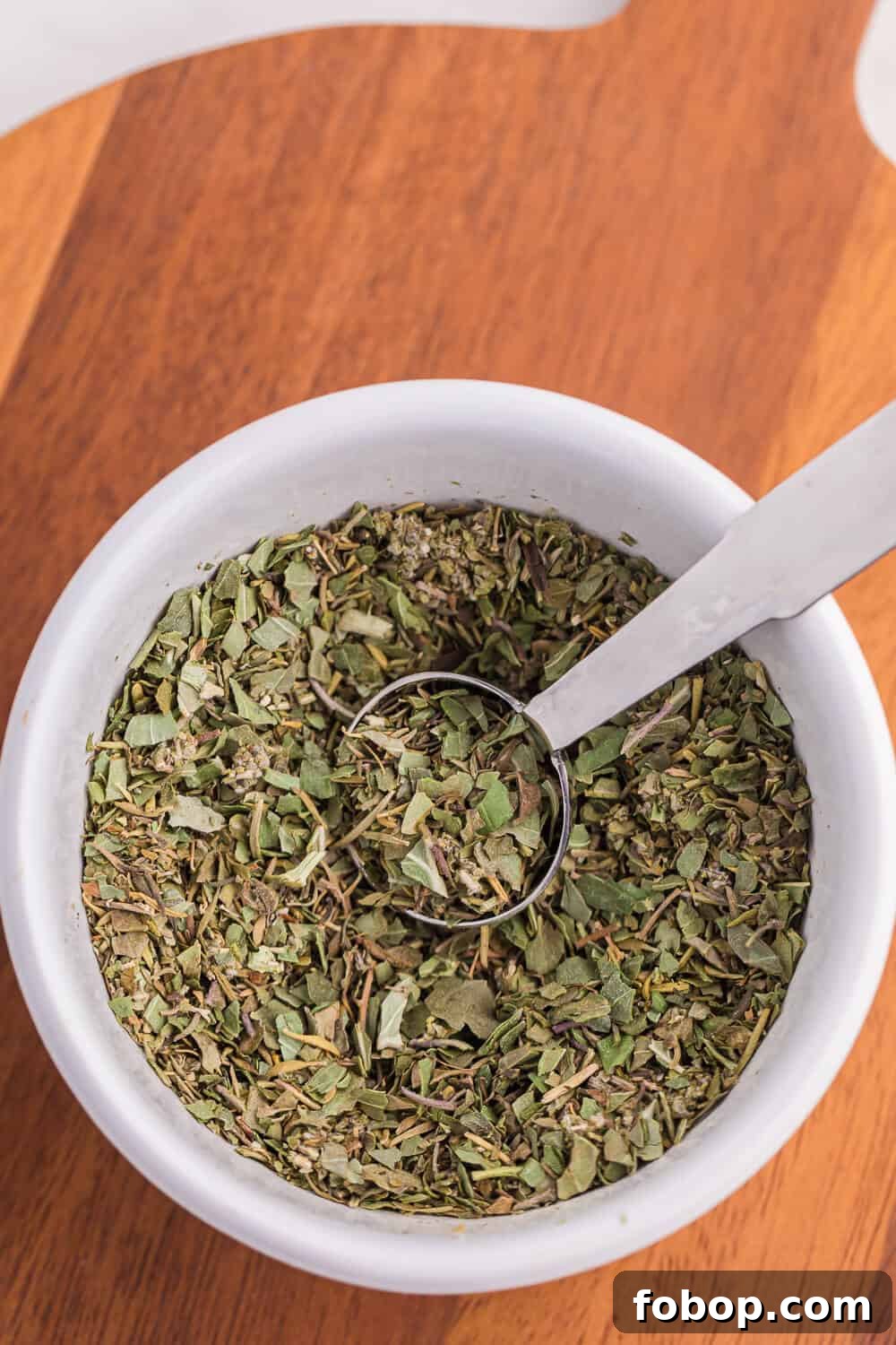 Italian seasoning in a bowl with a measuring spoon.