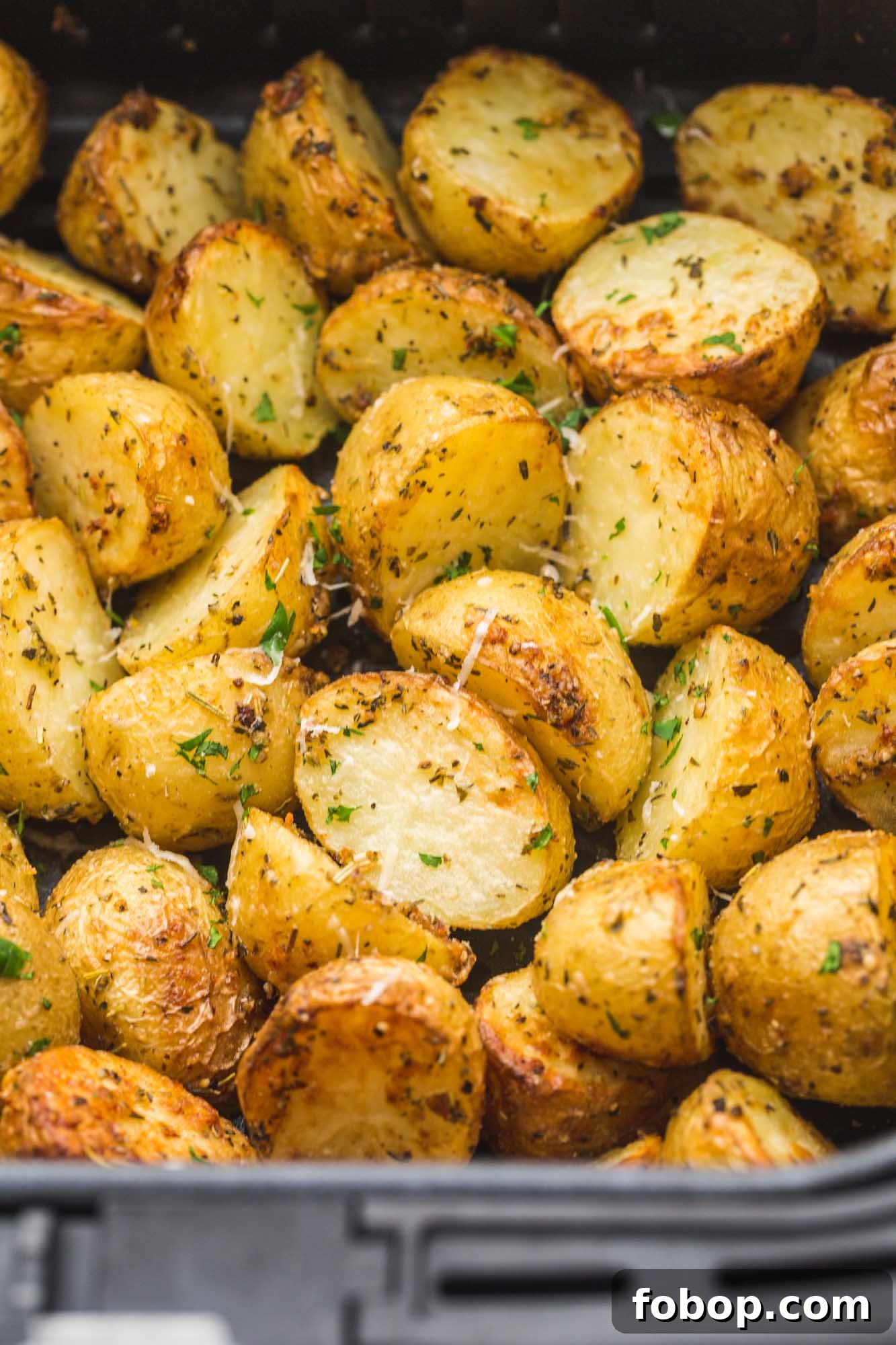 Crispy Air Fryer Roasted Potatoes with Garlic and Herbs 3 Roasted baby potatoes in an Air Fryer basket.