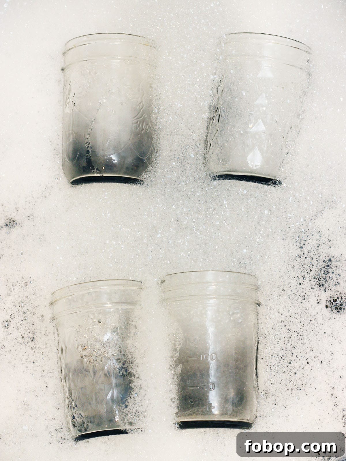four jars in a sink full of soapy water