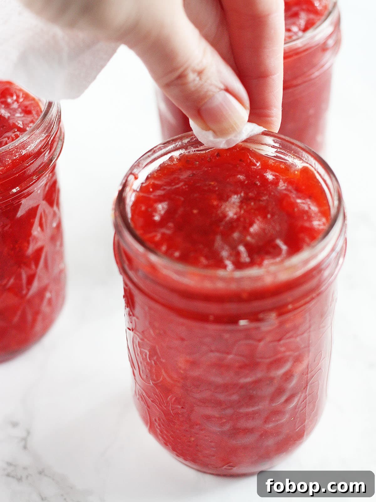 hand wiping the rims of filled jars