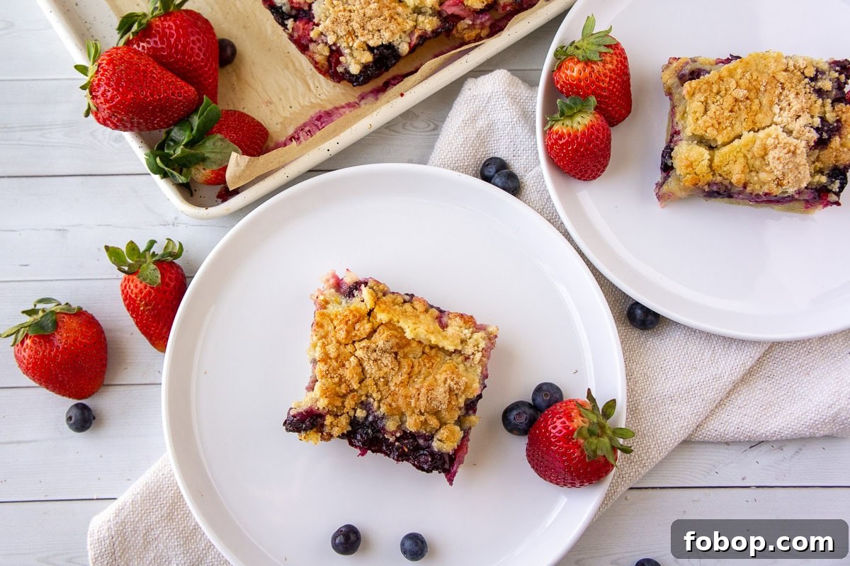 a pan of mixed berry cookie bars with two squares on white plates.