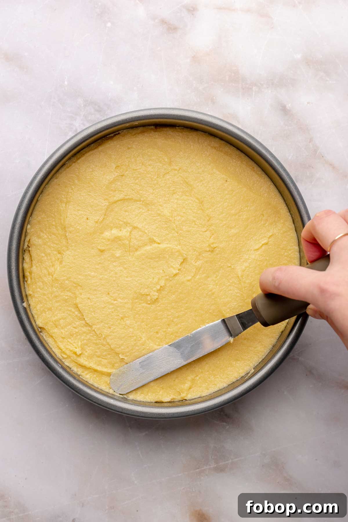 Coconut Almond Cake Recipe with Moist Layers and Toasted Almonds 9 A spatula smooths out almond cake batter in a bowl.