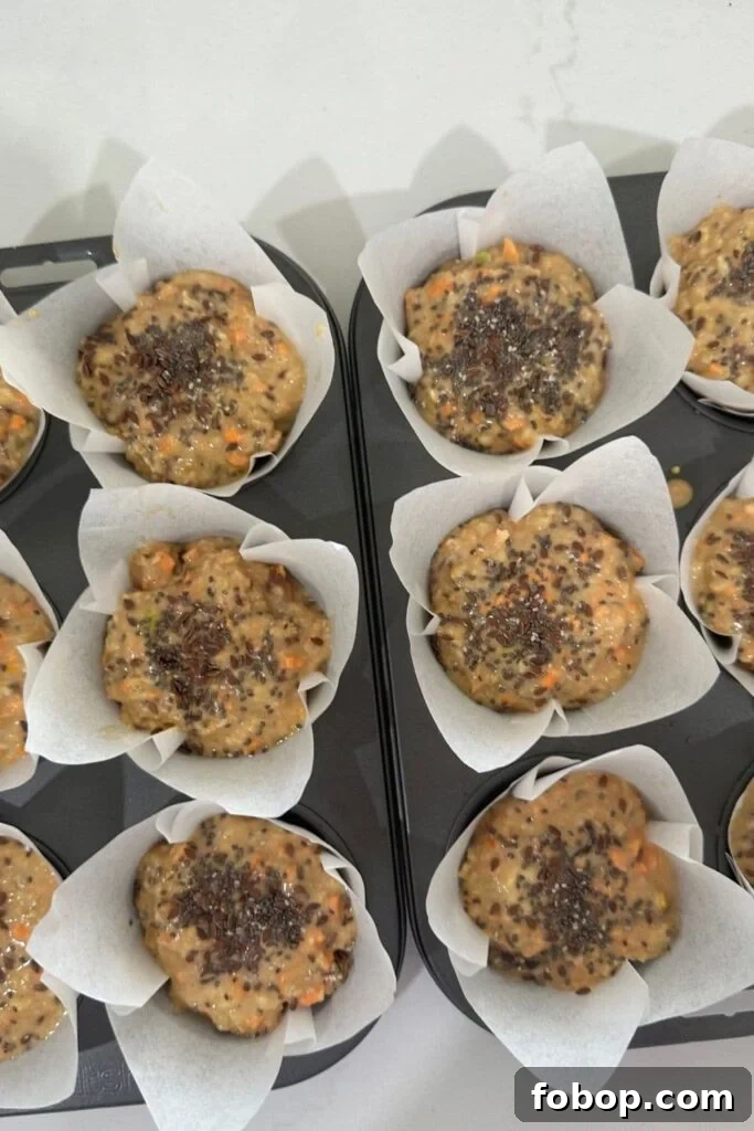 6 sourdough morning glory muffins that have not yet been baked. You can see the seed mixture that has been placed on top.