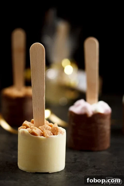 Hot chocolate sticks topped with fudge pieces and marshmallows surrounded by gold curling ribbon