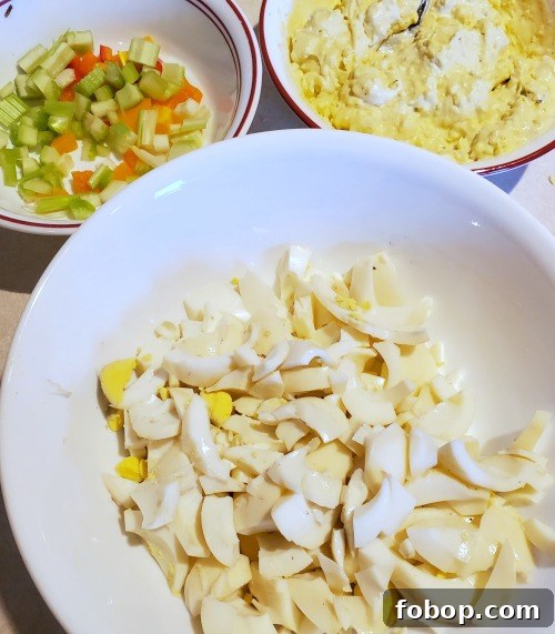 one bowl with chopped celery orange pepper, one with boiled egg whites, and one with egg salad wet ingredients