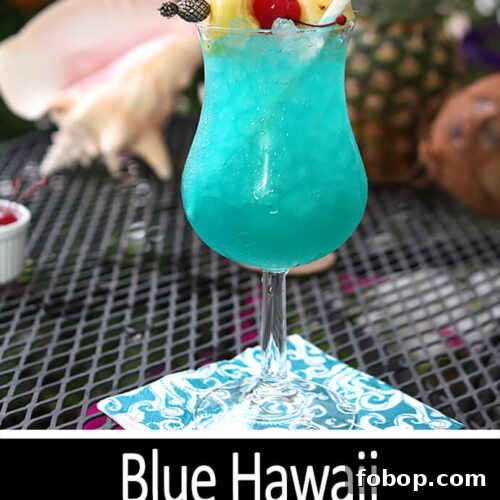 Blue Hawaii Cocktail served in a cocktail glass with both pineapple chunks and cherries for garnish.