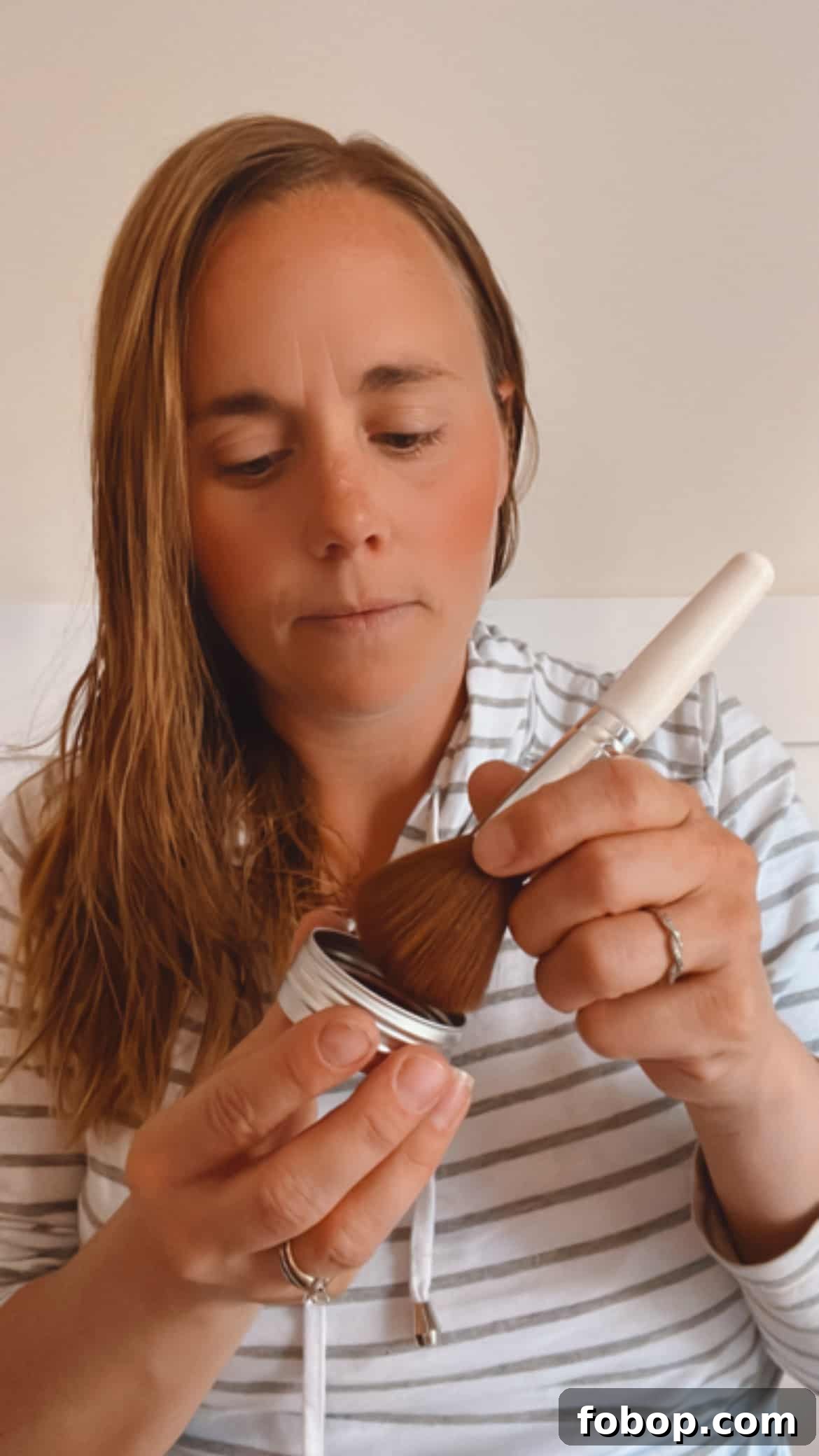 Make Your Own Natural Makeup: Simple DIY Recipes and Tips 2 Applying homemade blush with a small applicator.
