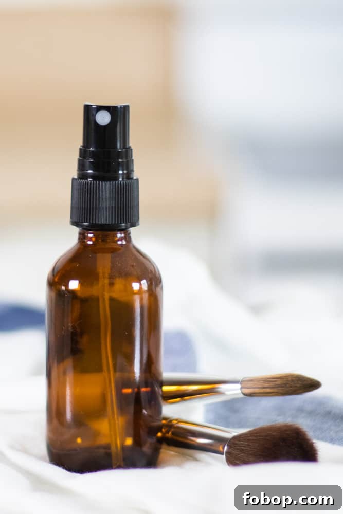 Make Your Own Natural Makeup: Simple DIY Recipes and Tips 7 glass spray bottle on white and blue towel with makeup brushes in background