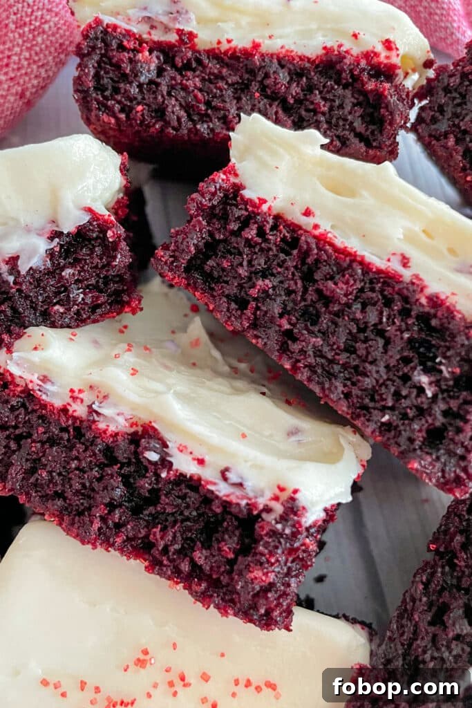 Red Velvet brownies with cream cheese frosting stacked beside eachother