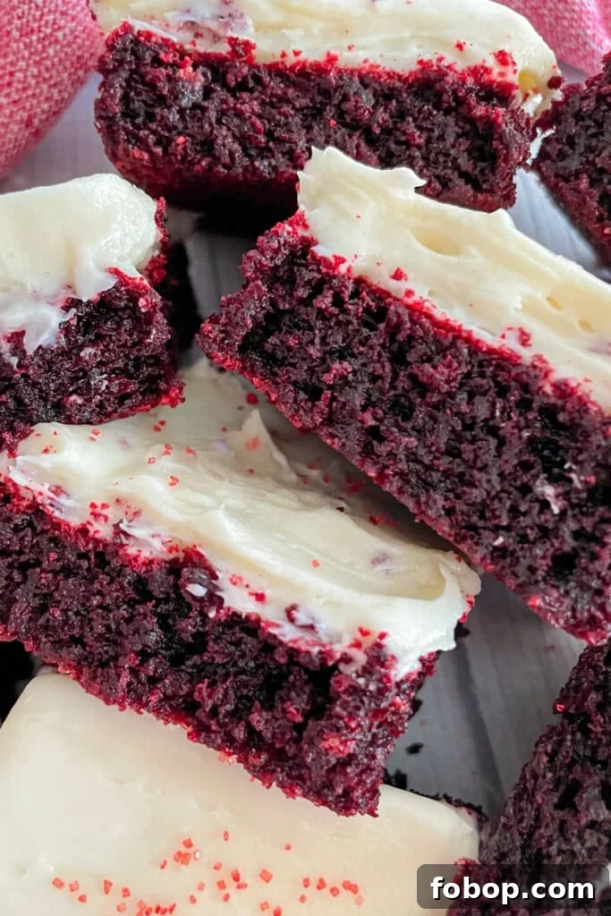 Red Velvet brownies with cream cheese frosting stacked beside eachother