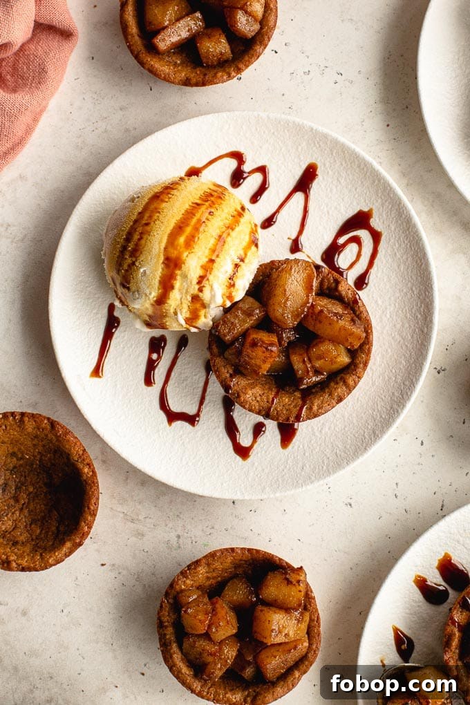 Up close view of a gingerbread cookie cup on a white plate with spiced pears and a scoop of ice cream.