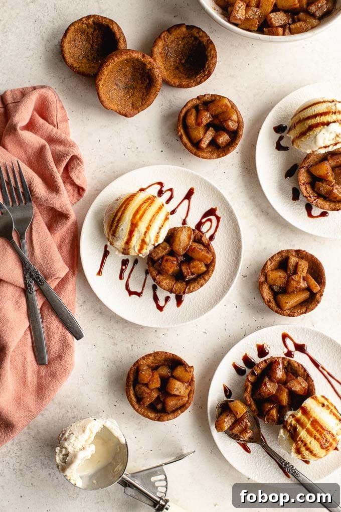 Overhead view of gingerbread cups arranged on white plates, and topped with spiced pears and ice cream.