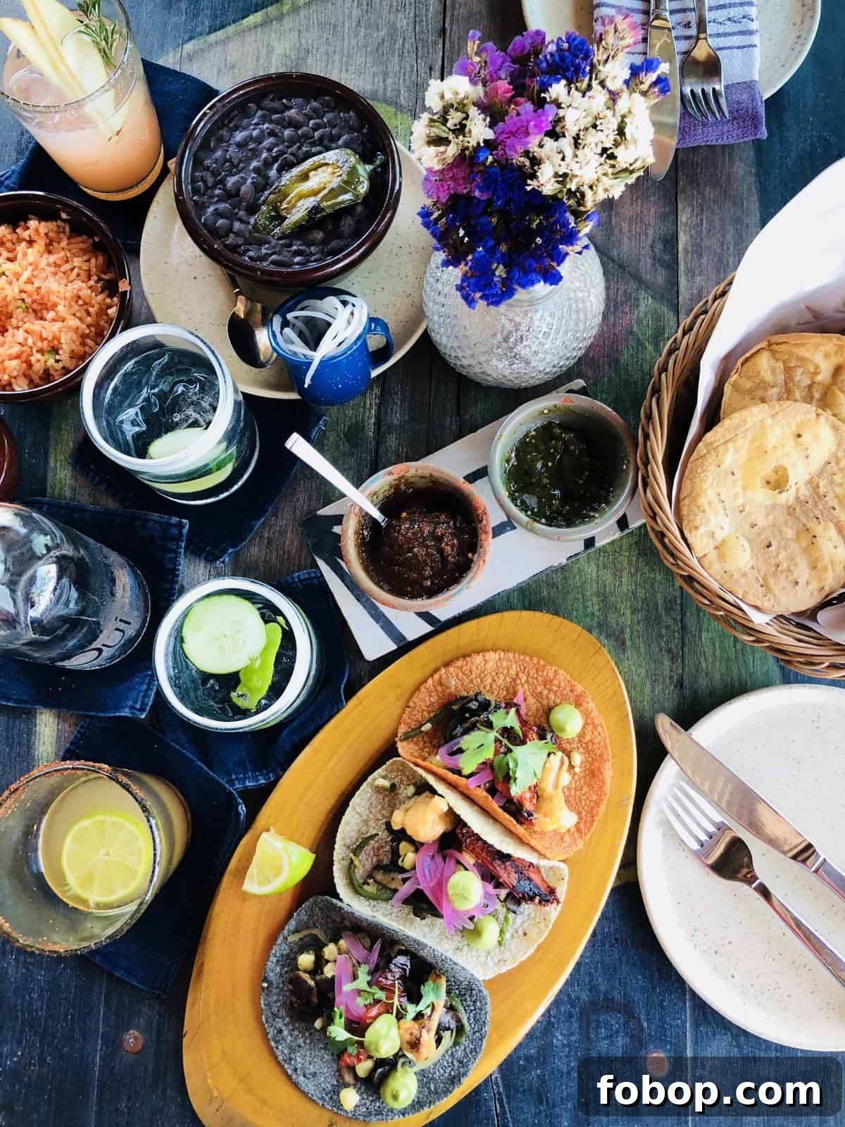 Tulum Travel Guide: Top Eats, Hotels, and Must-See Activities 11 Top down view of drinks, sauces and tacos on a table.