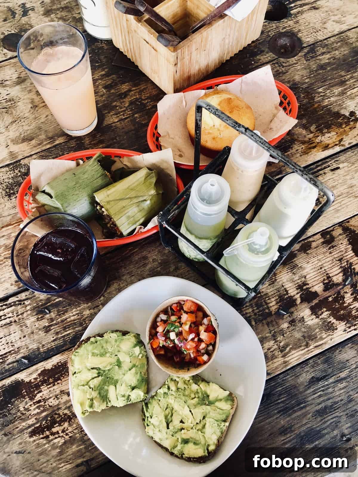 Tulum Travel Guide: Top Eats, Hotels, and Must-See Activities 10 Overhead view of plates and baskets of food on a wooden table.