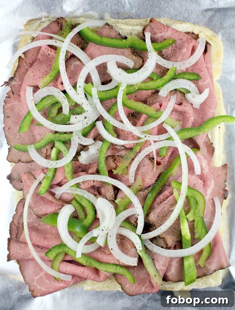 top down view on a half assembled recipe showing the roast beef, onion, and green bell pepper