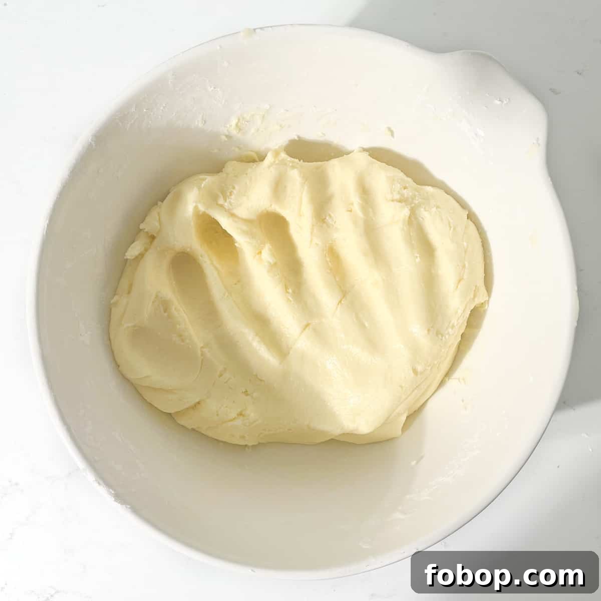 Mixed sequilho dough ready for rolling in a large white bowl.