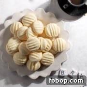 Sequilhos Brazilian cornstarch cookies on a white plate with coffee.