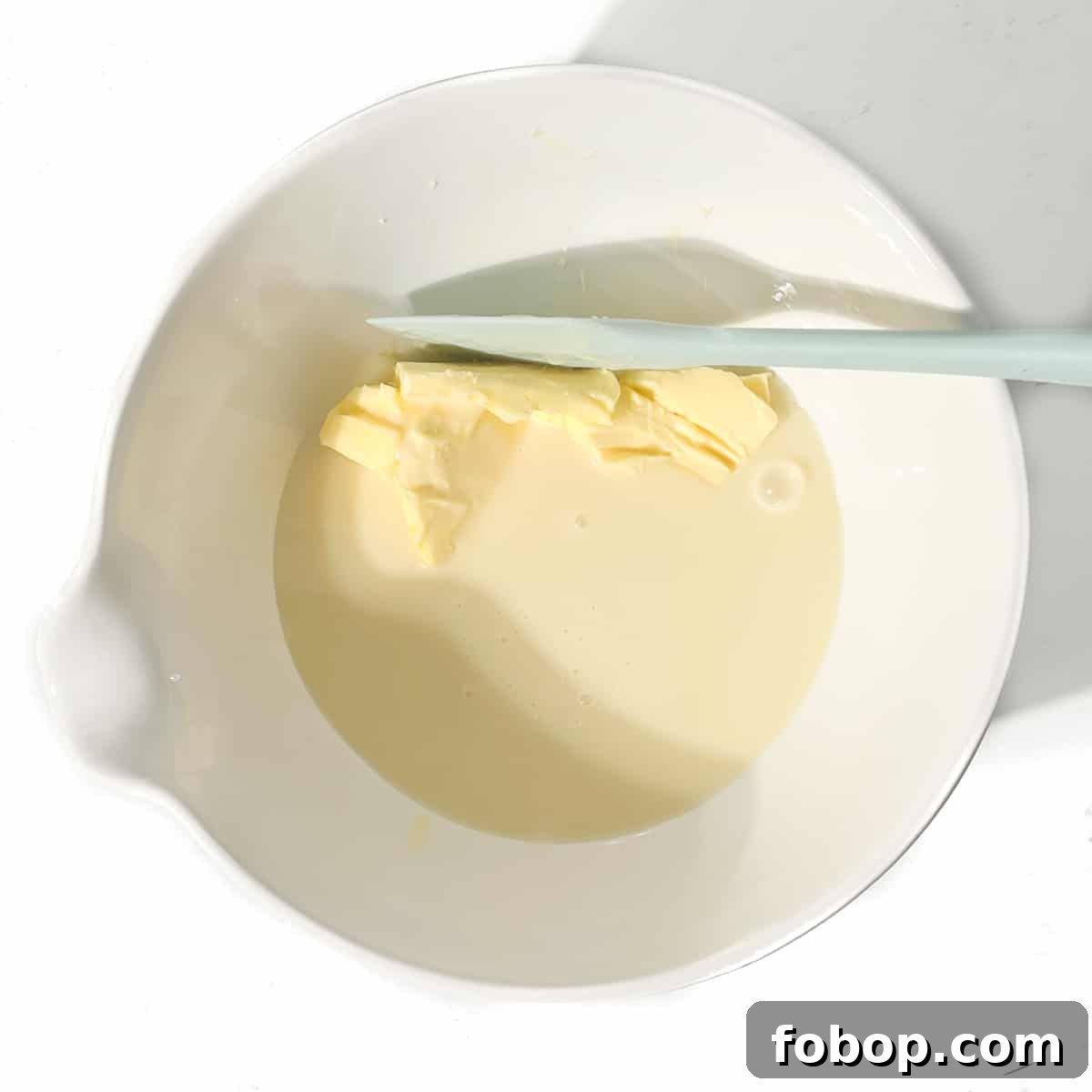 Adding condensed milk and butter to a large white bowl.