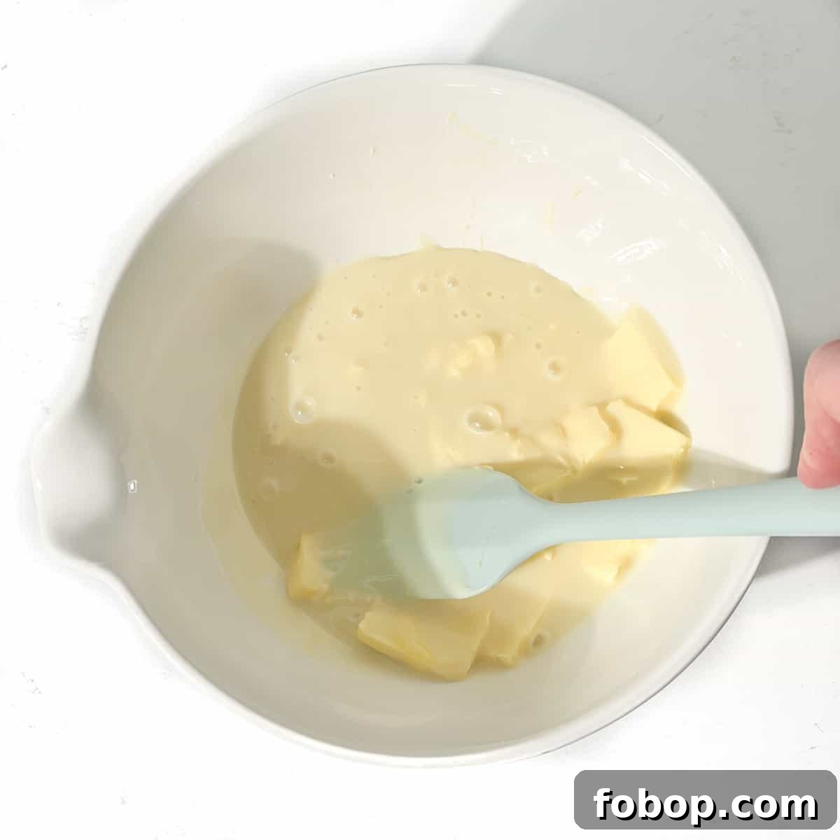 Mixing the butter and condensed milk for the sequilhos by hand with a spatula.