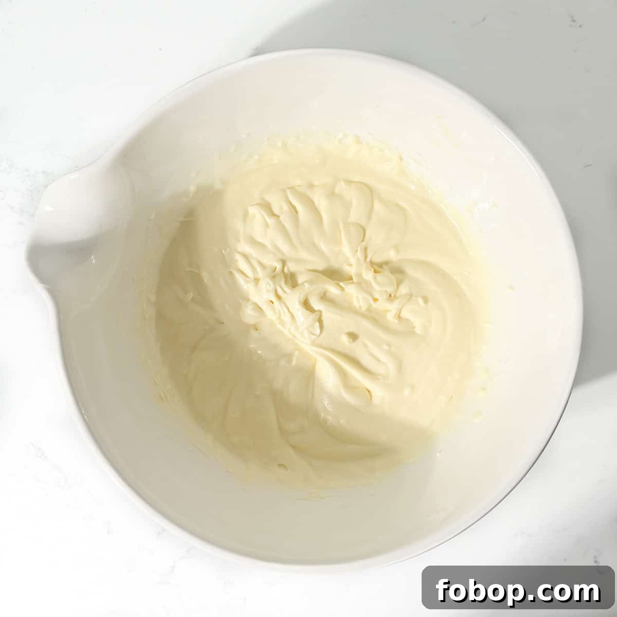 Mixed condensed milk and butter in a large white bowl.