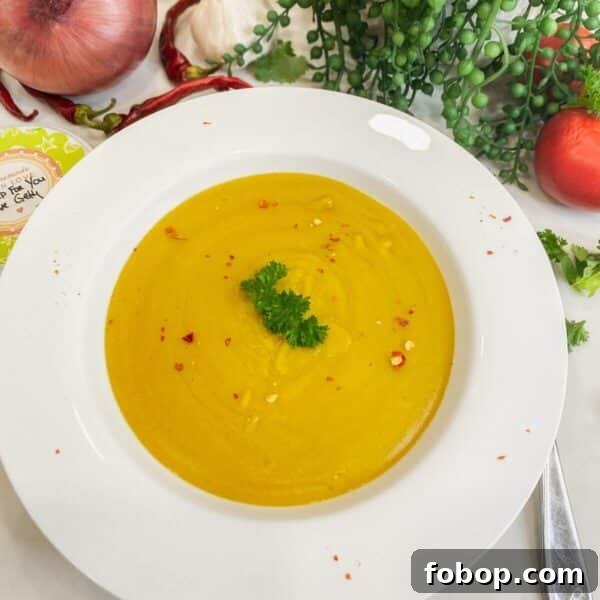 Split pea soup in bowl with veggies in the background.
