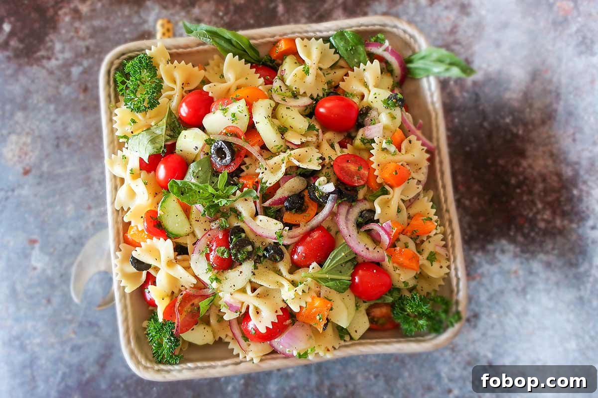 best summer pasta salad with olives, tomatoes, onions and herbs in a bowl