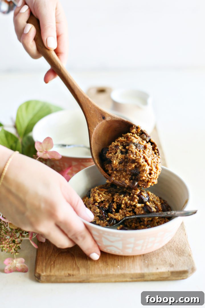 Tangerine Cherry Steel-Cut Overnight Oats Recipe 5 photo of a woman spooning cherry oatmeal into a bowl using a wooden spoon