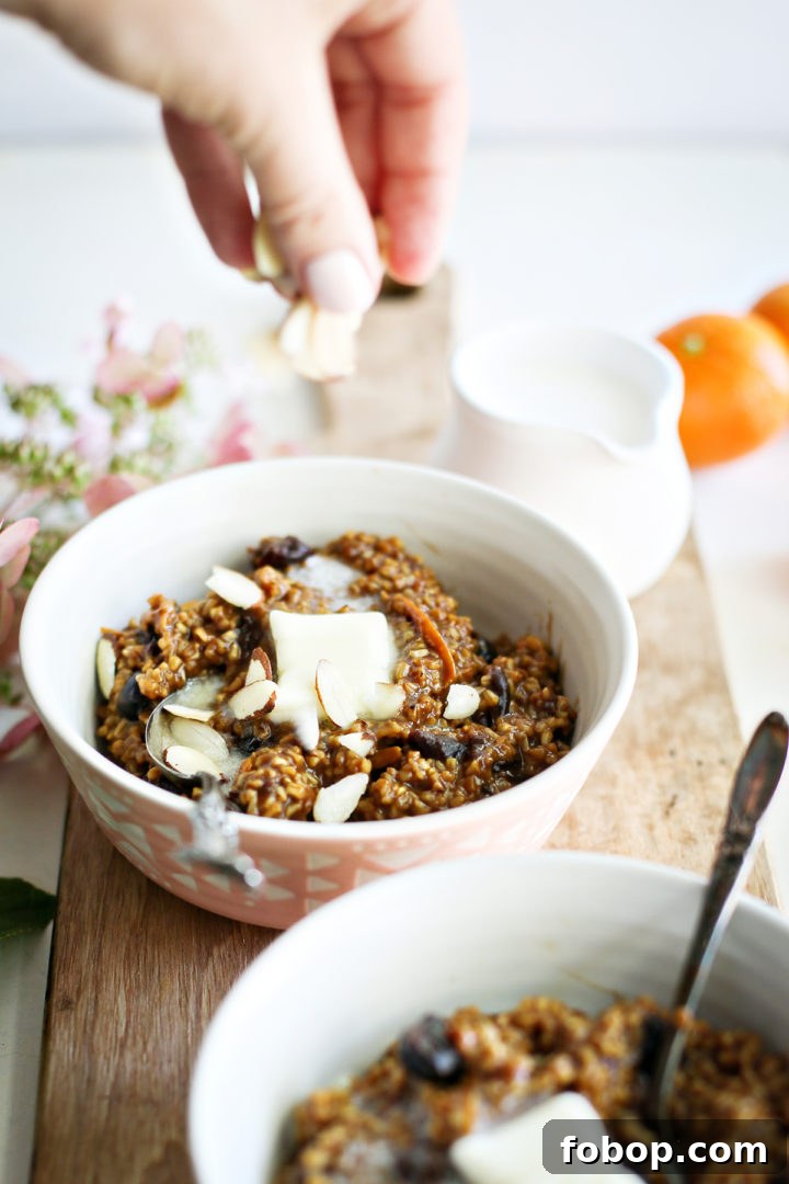 Tangerine Cherry Steel-Cut Overnight Oats Recipe 6 photo of a woman sprinkling sliced almonds onto a bowl of cherry oatmeal after making this recipe for overnight steel cut oats