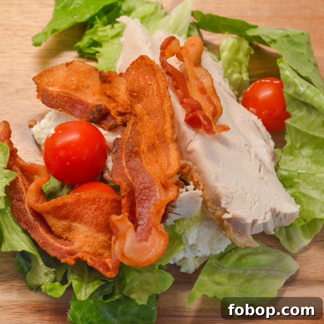 On a large cutting board, pile the chicken, bacon, lettuce, and tomatoes together. Use a sharp knife or mezzaluna to finely chop everything into small, bite-sized pieces.