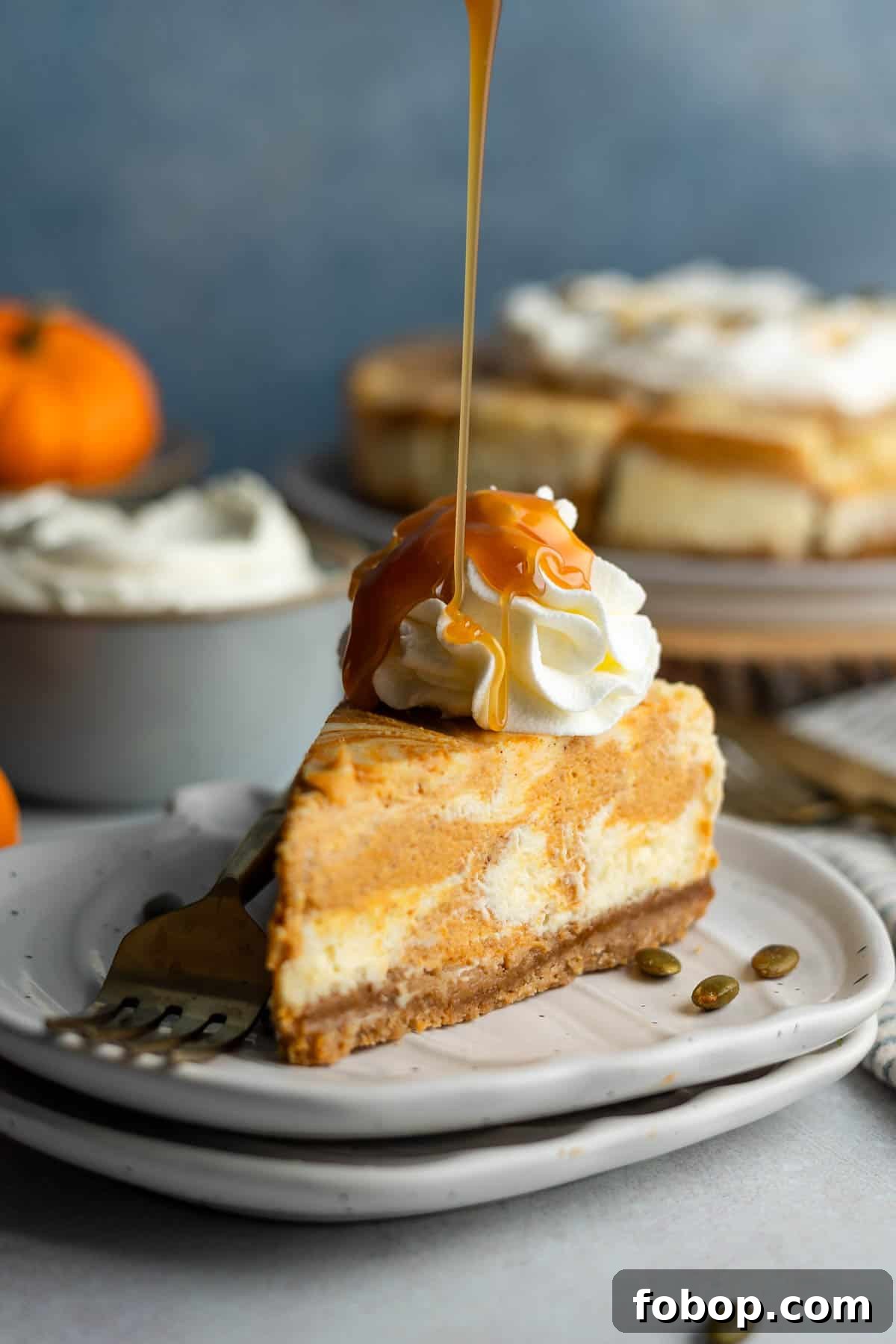 Caramel drizzling down onto a slice of gluten-free cheesecake swirled with pumpkin. 