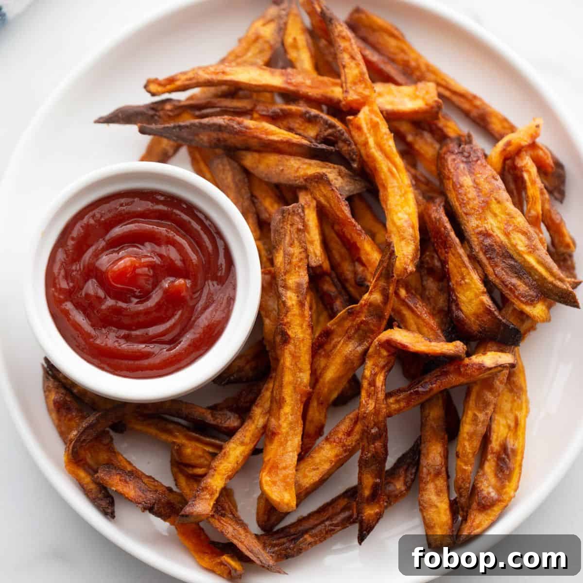 Crispy Air Fryer Sweet Potato Fries Recipe 2 Plate of crispy golden brown air fryer french fries served with ketchup.