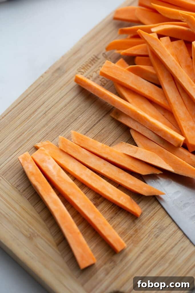 Crispy Air Fryer Sweet Potato Fries Recipe 5 Sweet potato fries on a wooden cutting board.
