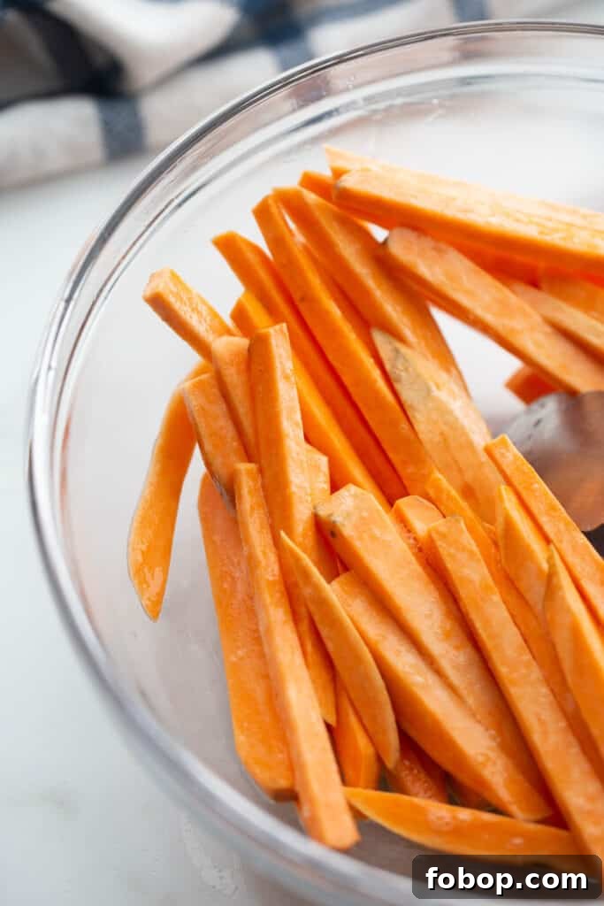 Crispy Air Fryer Sweet Potato Fries Recipe 6 Hand cut sweet potatoes in a glass bowl.