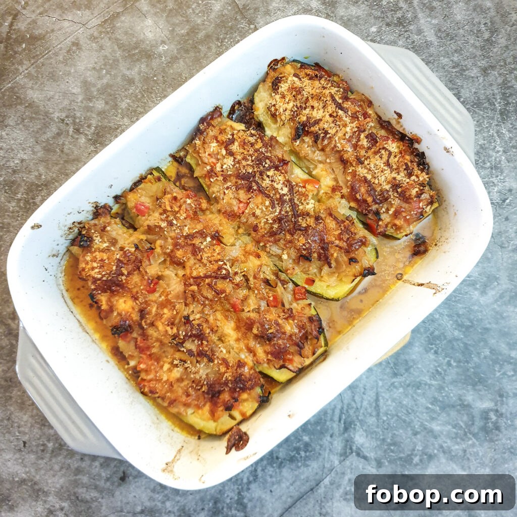 4 baked stuffeed courgettes in a baking dish.