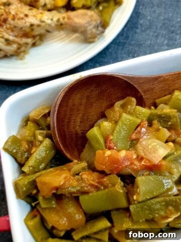 A dish of Middle Eastern-style runner beans with a wooden serving spoon.