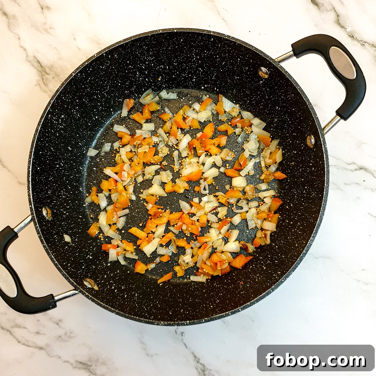 Diced red peppers and onions in a frying pan.