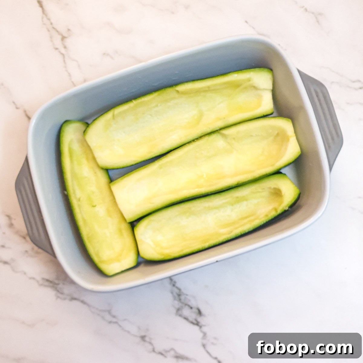4 hollowed out courgettes in a baking dish.