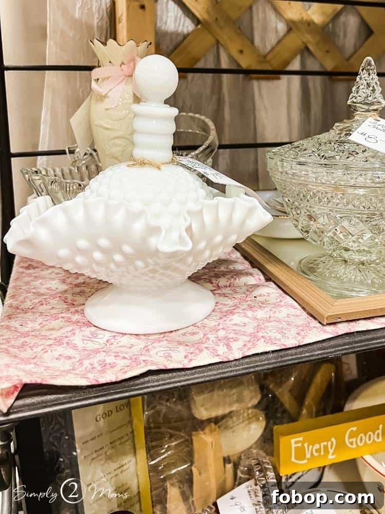 Milkglass pedestal bowl and milkglass perfume bottle displayed in an antique store.