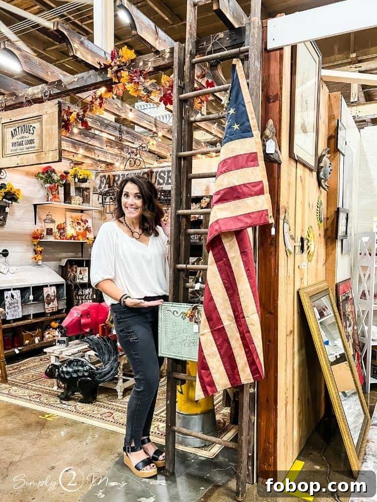 AnnMarie from Simply2Moms standing with a vintage wood painter's ladder in an antique mall booth.