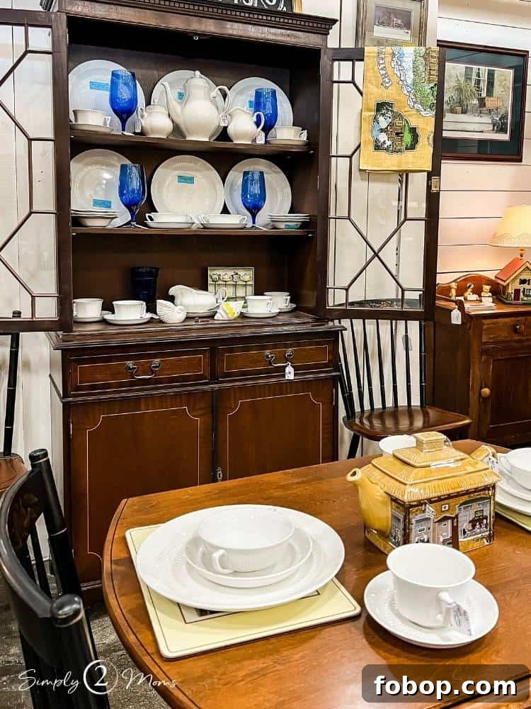 Antique hutch displaying vintage ironstone and blue stemware at an antique mall.