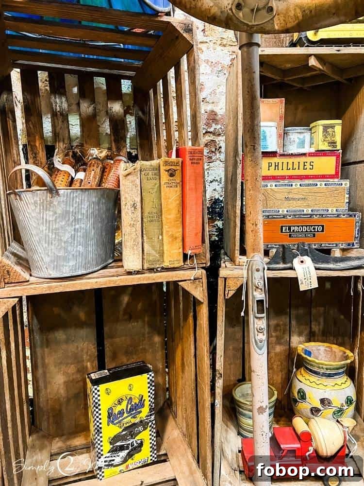 Vintage books, cigar boxes, wooden spools, and other antiques displayed in wood crates at a shop.