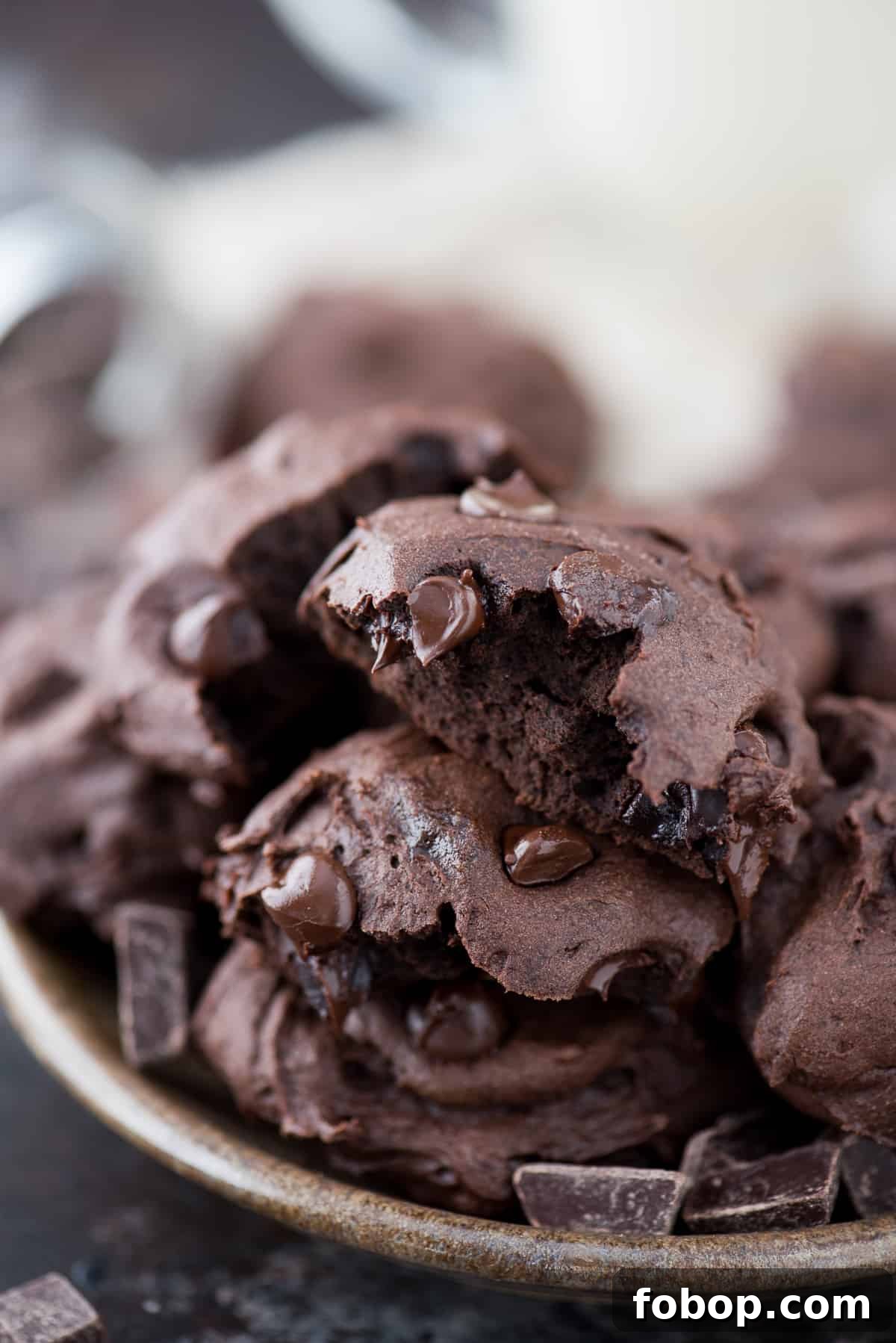 Healthier Dark Chocolate Coconut Oil Cookies A bitten out of healthier dark chocolate coconut oil cookie on top of other cookies in a plate.