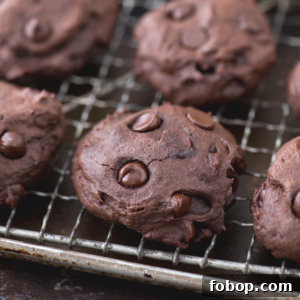 Close-up of thick, soft healthier chocolate cookies with chocolate chips, cooling on a metal wire rack.