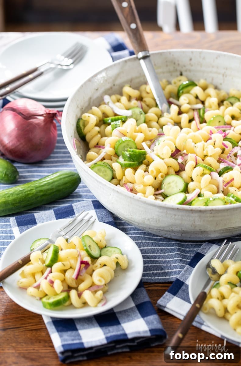 cucumber pasta salad served in a large bowl with two servings on small white plates.
