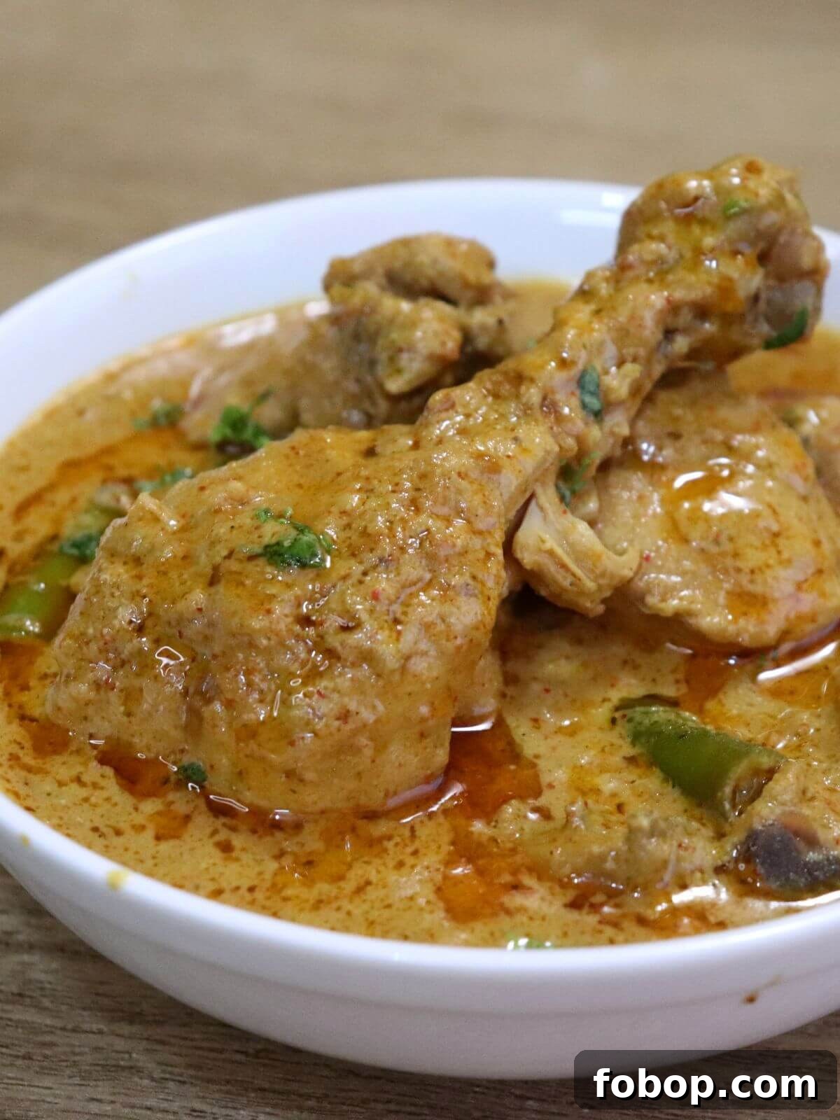 chicken korma curry served in a white colored bowl.